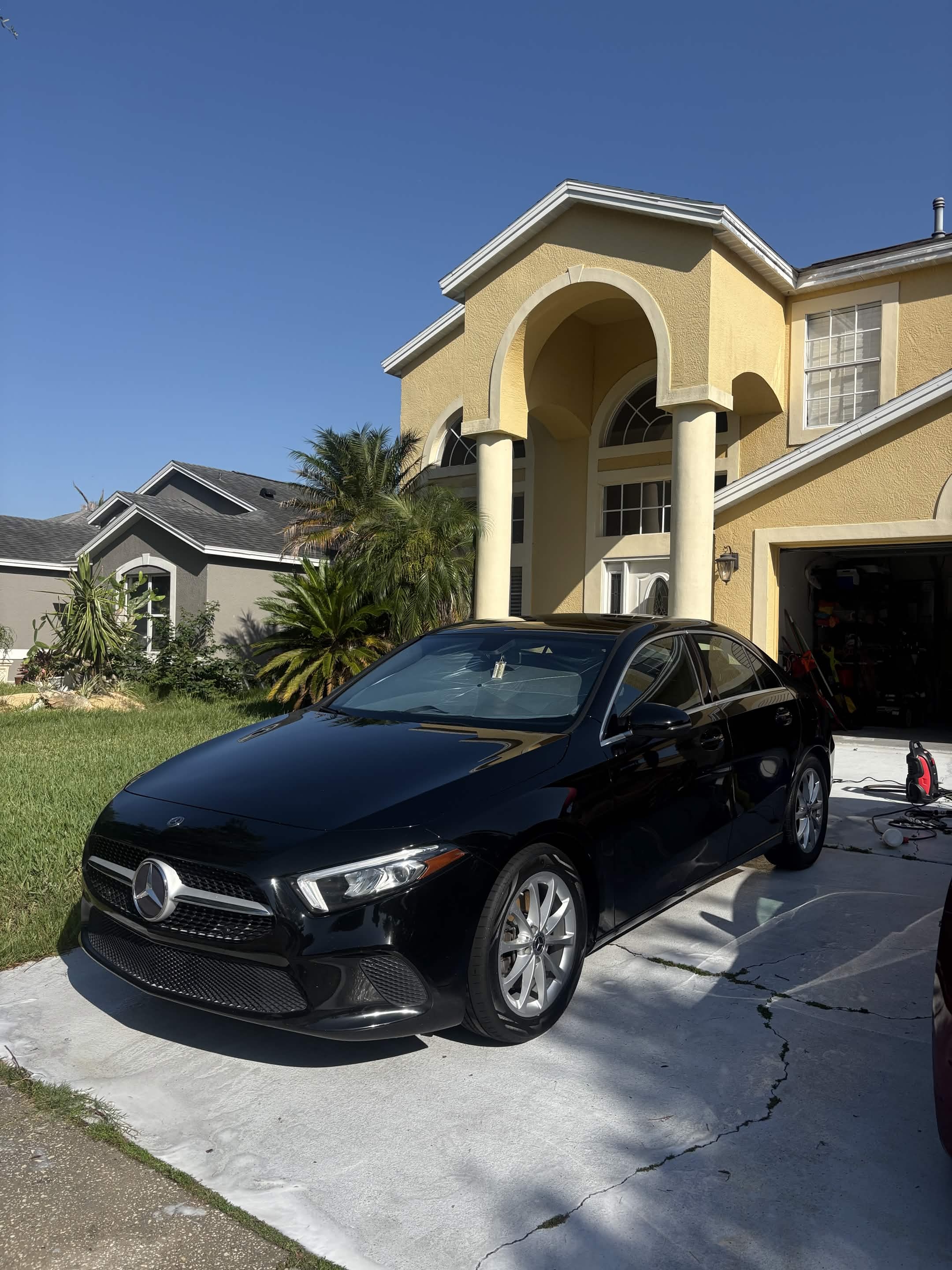 Glossy black Mercedes-Benz sedan after a full detail in a Melbourne, FL driveway