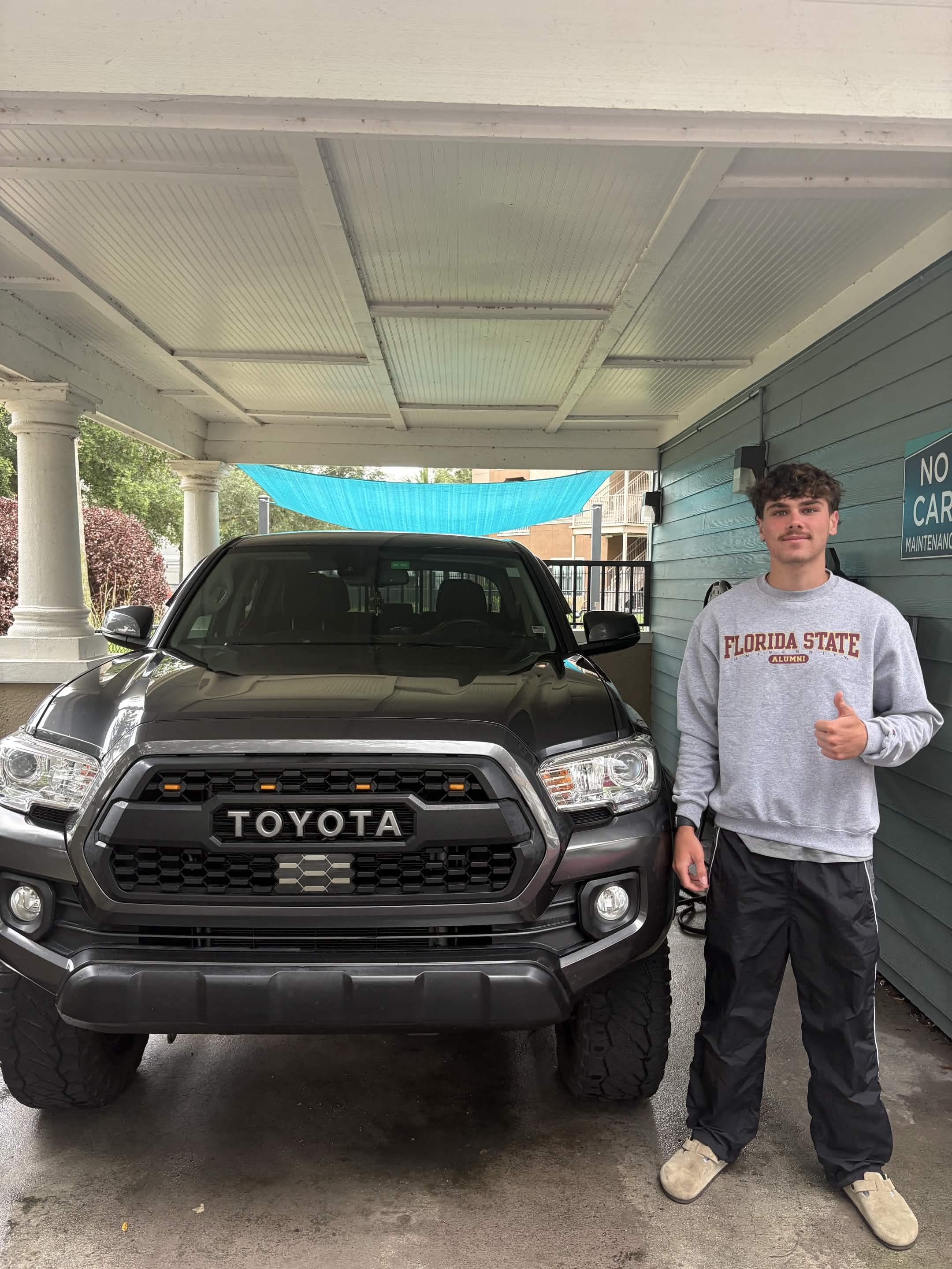Nicky, owner of NickyDoesDetailing, beside a freshly detailed Toyota Tacoma